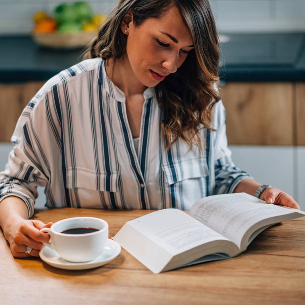 жінка п'є каву і читає книгу
 - Фото, зображення