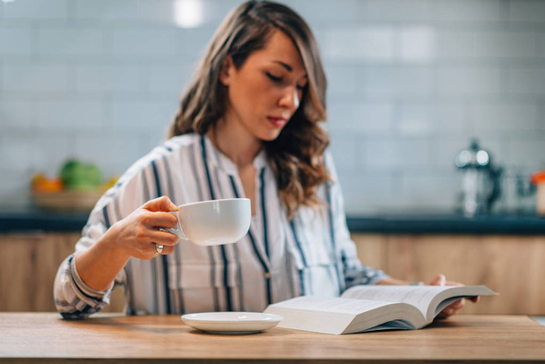 vrouw drinken koffie en lezen boek - Foto, afbeelding