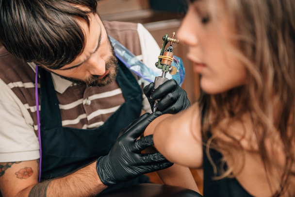 El tatuador se centró en su trabajo. Imagen tonificada
 - Foto, Imagen