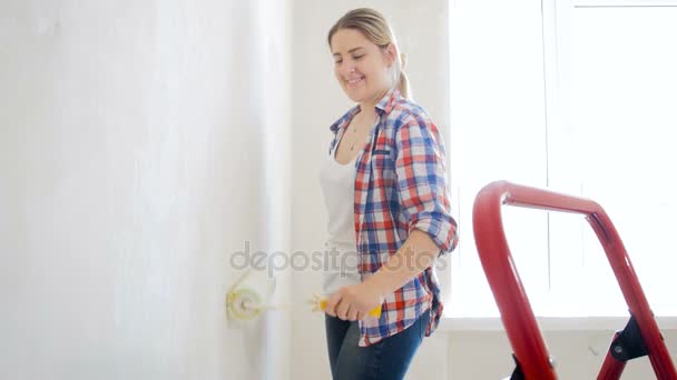 Imágenes de 4k de la hermosa mujer sonriente pintando la pared con el rodillo en el nuevo hogar
 - Imágenes, Vídeo