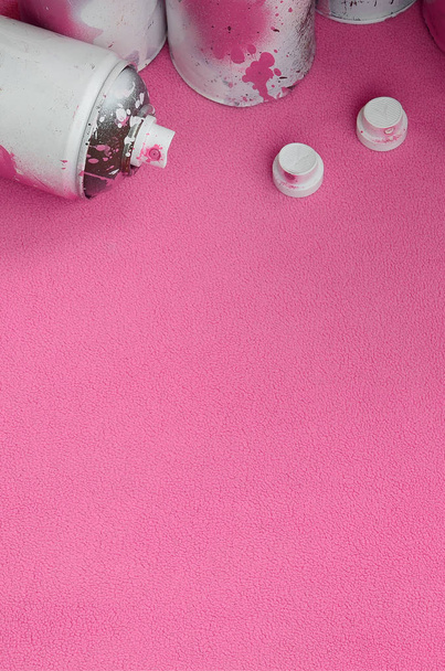 Niektóre używane aerozolu różowy spray puszki i dysze z farba kapie leży na kocu tkaniny miękkie i furry światło różowy Polar. Klasyczne kobiece kolor. Koncepcja chuligaństwa graffiti - Zdjęcie, obraz