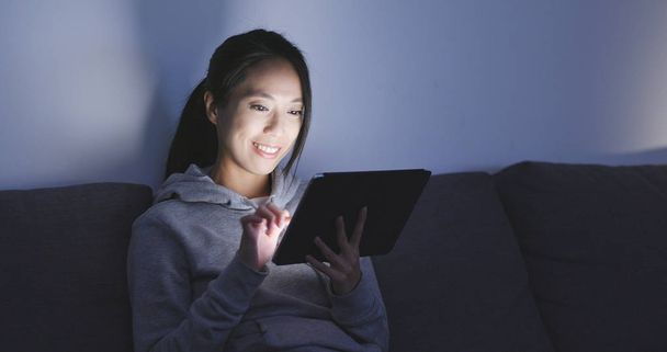Mujer mirando la tableta digital en casa por la noche, mira la tableta digital
  - Foto, Imagen