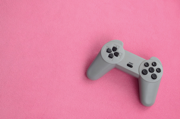 Spielkonzept. Single Pad Joystick liegt auf der Decke aus pelzigen rosa Fleece-Stoff. Controller für Videospiele auf einer Hintergrundstruktur aus hellrosa weichem Plüsch-Fleece-Material - Foto, Bild