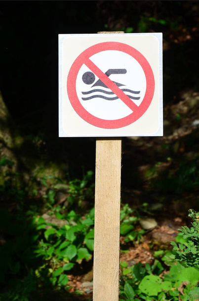 Een zuil met een teken ter aanduiding van een verbod op zwemmen. Het bord toont een doorgekruiste zwevende persoon - Foto, afbeelding