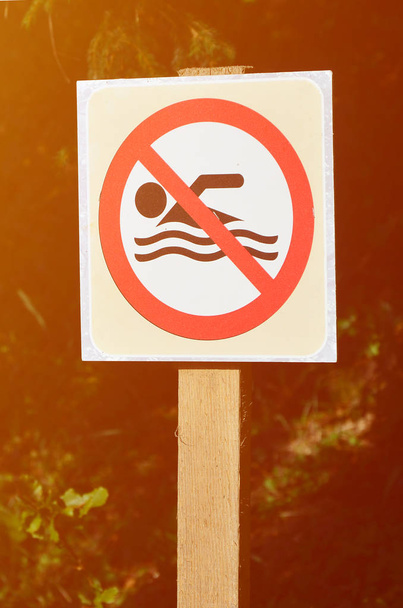 Pilíř se znaménkem označující zákaz plavání. Znaménko ukazuje přeškrtnutý plovoucí osoba - Fotografie, Obrázek