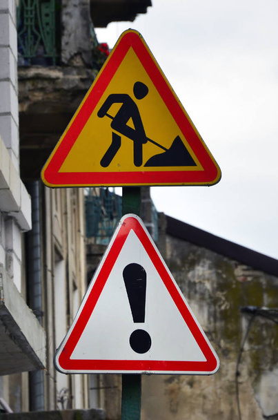 Znaki drogowe z wykrzyknikiem i człowiek kopanie ziemi. Trwają roboty drogowe - Zdjęcie, obraz
