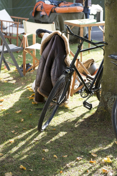 Ποδήλατο από ένα δέντρο με παλτό και έπιπλα στο παρασκήνιο - Φωτογραφία, εικόνα