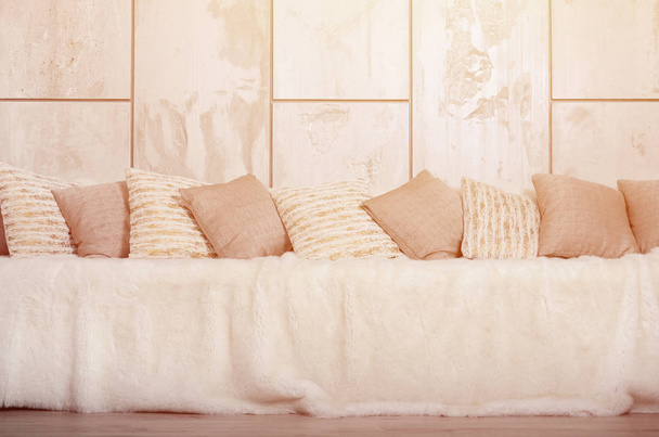 Muchas almohadas se encuentran en el sofá, que está cubierto con un gran velo de felpa contra el fondo de una pared de mármol
 - Foto, Imagen