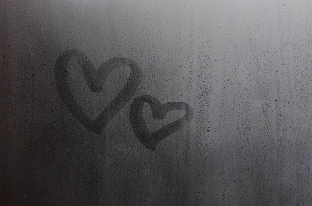 Couple of abstract blurred love heart symbol drawn by hand on the wet window glass with sunlight background. Template for Valentine Day postcards - Photo, Image