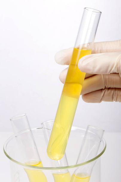 Εργαστήριο κυλίνδρων και ποτήρι ζέσεως στο χέρι που απομονώνονται σε λευκό φόντο - Φωτογραφία, εικόνα