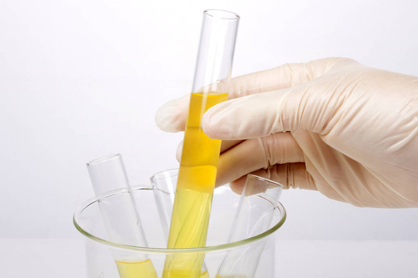 Cilindros de laboratorio y vaso de precipitados en mano aislados sobre fondo blanco
 - Foto, Imagen