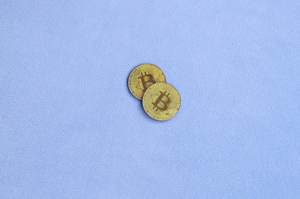 Δύο χρυσά bitcoins βρίσκεται σε ένα κάλυμμα από ύφασμα μαλακό και αφράτο ελαφρύ μπλε δέρας. Φυσική απεικόνιση των εικονικό νόμισμα κρυπτό - Φωτογραφία, εικόνα