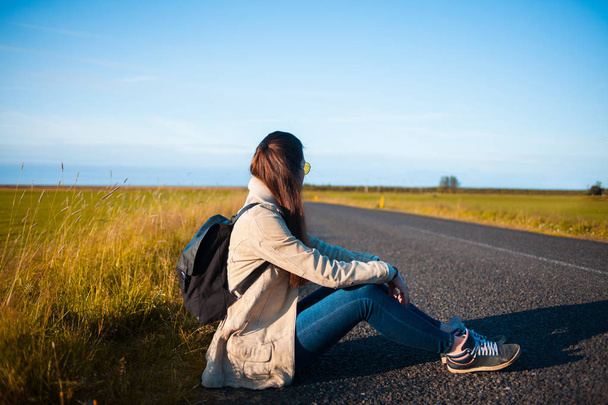 Young woman tourist sits on the road. - Φωτογραφία, εικόνα