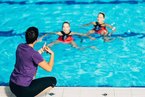 Nadadores sincronizados con entrenador en la piscina
  - Foto, imagen