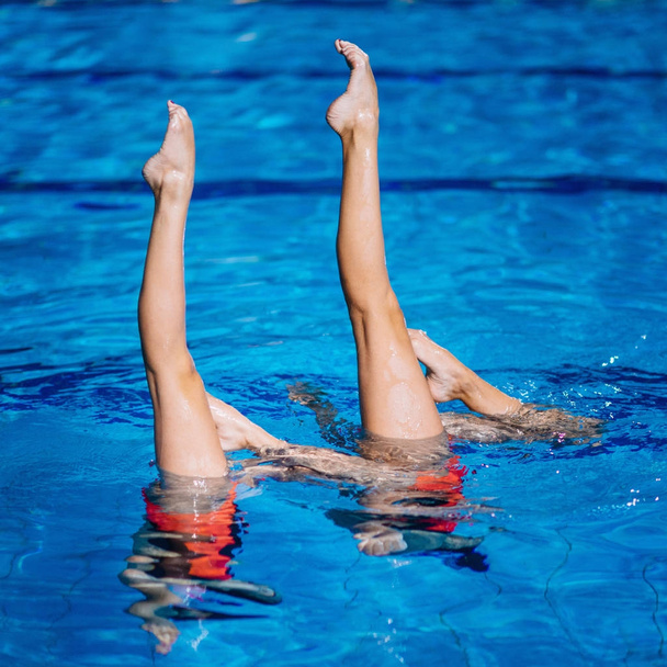 Синхронізований плавальний дует під час виконання в басейні
 - Фото, зображення