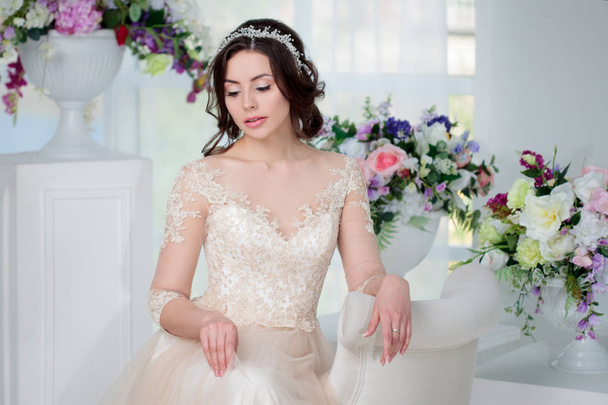 Portrait of beautiful girl in a luxurious wedding dress. Interior decorated with flowers - Zdjęcie, obraz