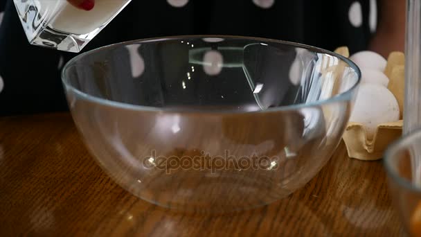 A woman in the kitchen to cook. Milk pouring in bowl - Πλάνα, βίντεο
