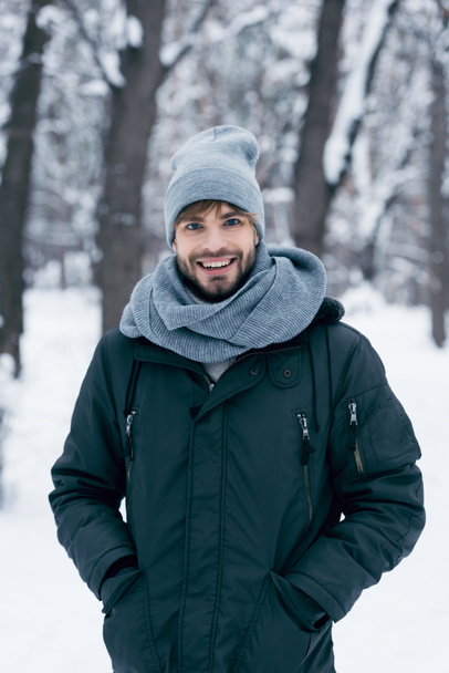 portrait of handsome smiling man looking at camera in winter park - Photo, Image