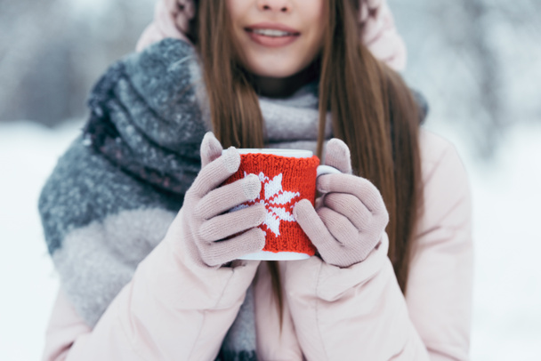 enfoque selectivo de la mujer con taza de café caliente en las manos en el parque nevado
 - Foto, Imagen