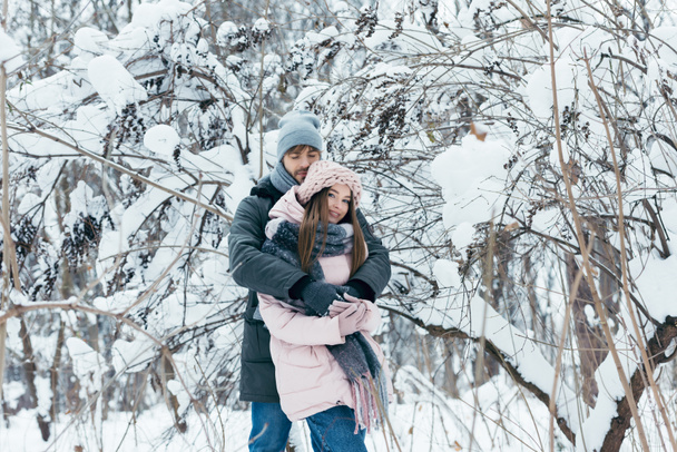 a fiatalember átölelve barátnője téli erdőben - Fotó, kép