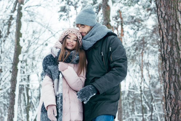 young man hugging girlfriend in winter forest - Foto, Imagem