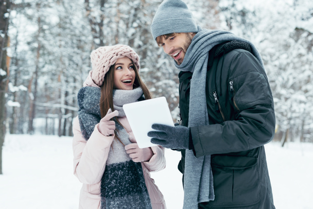 retrato de pareja feliz joven con la tableta en el parque cubierto de nieve
 - Foto, imagen