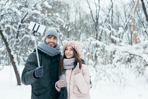smiling couple taking selfie together on smartphone in winter park - Photo, Image