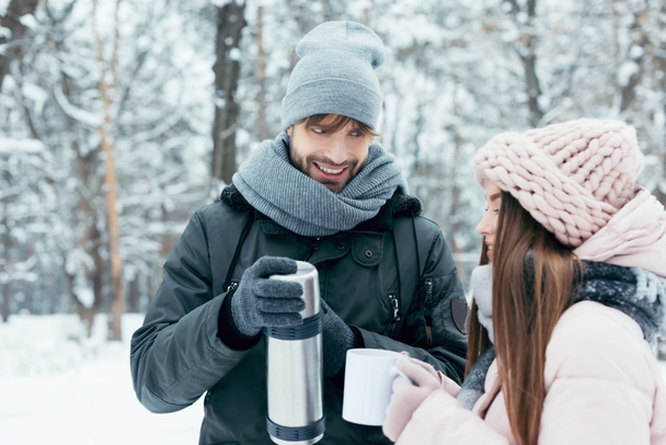 young couple drinking tea from thermos in winter park - Φωτογραφία, εικόνα
