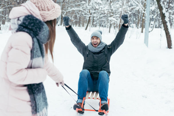 partial view of young couple sledging together on winter day in park - 写真・画像