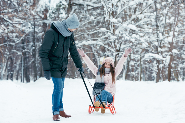 young couple sledging together on winter day in park - Photo, Image
