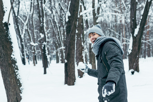 portrait of happy young man playing with snow in winter park - Foto, imagen