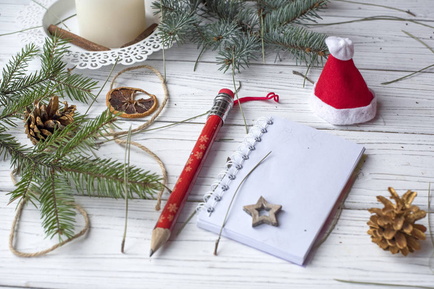 A festive winter mock up photo with a fir twigs, an opened note book, an old book, a pencil, cones, a candle and decation elements - Fotoğraf, Görsel