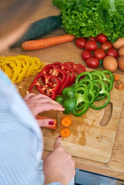 Крупным планом молодая женщина режет фрукты и овощи, чтобы сделать себе здоровый сок дома
 - Фото, изображение