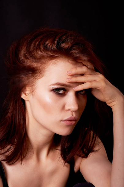 Girl in Studio on dark background.Red hair, great figure. Mysterious, arms crossed around the lips. The pensive look - Foto, Bild