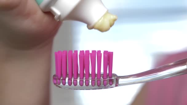 Mačkání zubní pastu z tuby na kartáček na zuby. Makro, detail 4k. Zpomalený pohyb, kopie prostor - Záběry, video
