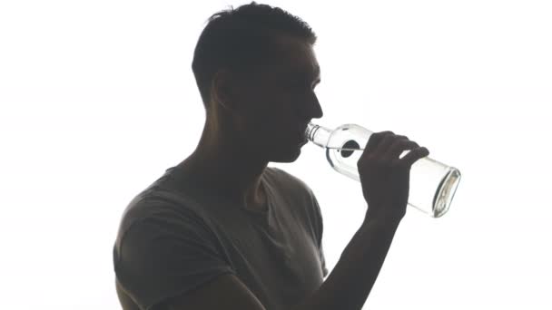Beyaz arka plan üzerinde izole bir şişe votka içme bir sarhoş adam silüeti - Video, Çekim