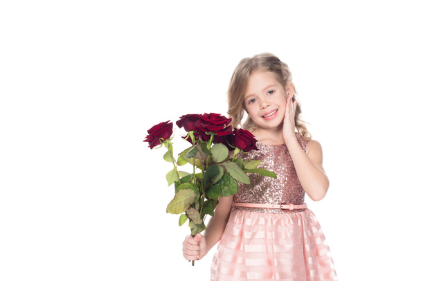adorable kid in dress holding bouquet of red roses, isolated on white - Foto, afbeelding