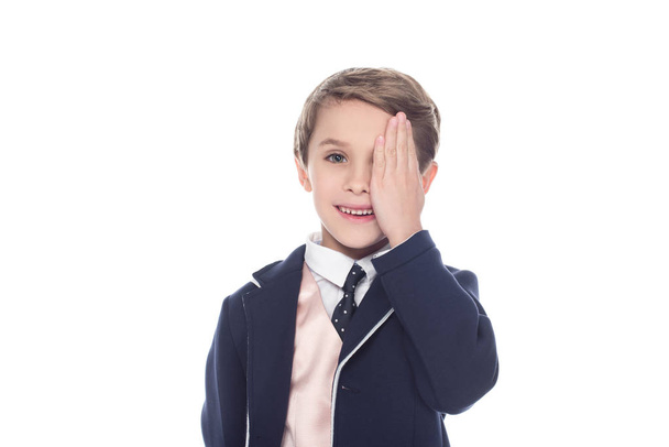cute little boy closing eye with palm and smiling at camera isolated on white - Photo, Image