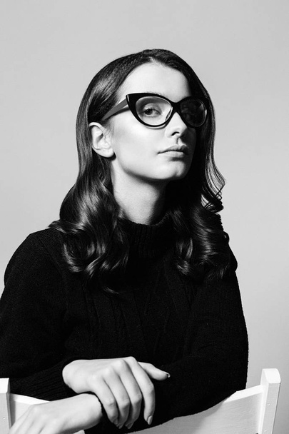 Portrait of pretty young brunette woman in stylish eyeglasses posing in studio - Fotó, kép