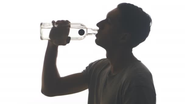 silueta de un hombre borracho bebiendo vodka de una botella aislada sobre fondo blanco
 - Metraje, vídeo