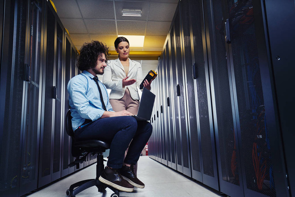 two young technicians working at a data center on server maintenance - Foto, Imagen