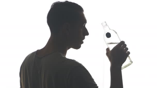 Boğaz beyaz arka plan üzerinde izole bir şişe votka içme bir sarhoş adam silüeti - Video, Çekim