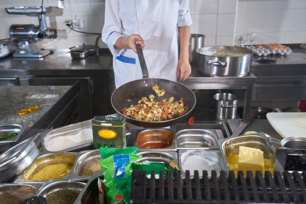 Шеф-кухар обприскування спецій на страві на комерційній кухні
 - Фото, зображення