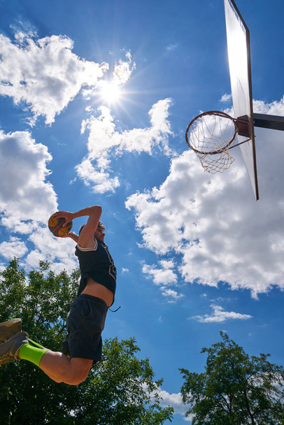 Jugador de baloncesto en acción volando alto y anotando
 - Foto, Imagen