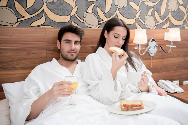hotel, travel, relationships, and happiness concept - happy couple in bed - Foto, afbeelding
