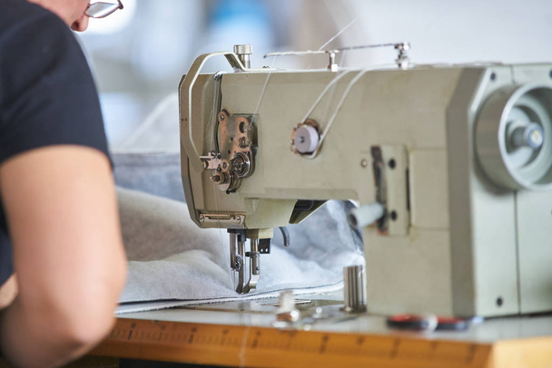 Seamstress or worker in a factory sewing with a industrial sewing machine - Foto, Bild