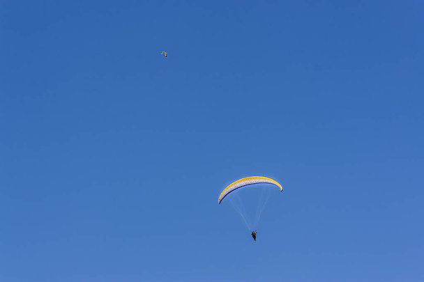 ejtőernyős magas repül az égen egy ejtőernyős és szórakoztató és ellazul. repülő egy ejtőernyős az ember élvezi a világ nagy a nyári kék ég háttér - Fotó, kép