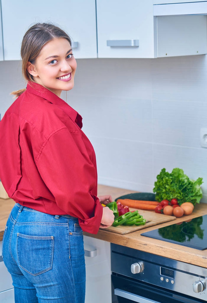 Closeup of a young woman cutting some fruit and vegetables to make herself a healthy juice at home - Photo, Image