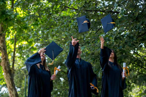 educação, graduação, conceito de pessoas - grupo de estudantes internacionais felizes em placas de argamassa e vestidos de solteiro com diplomas
 - Foto, Imagem