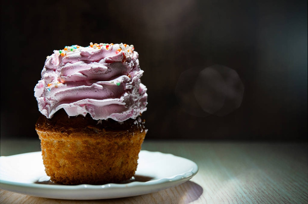 Yummy cupcake with buttercream on wooden table against dark background with copy space. - Valokuva, kuva